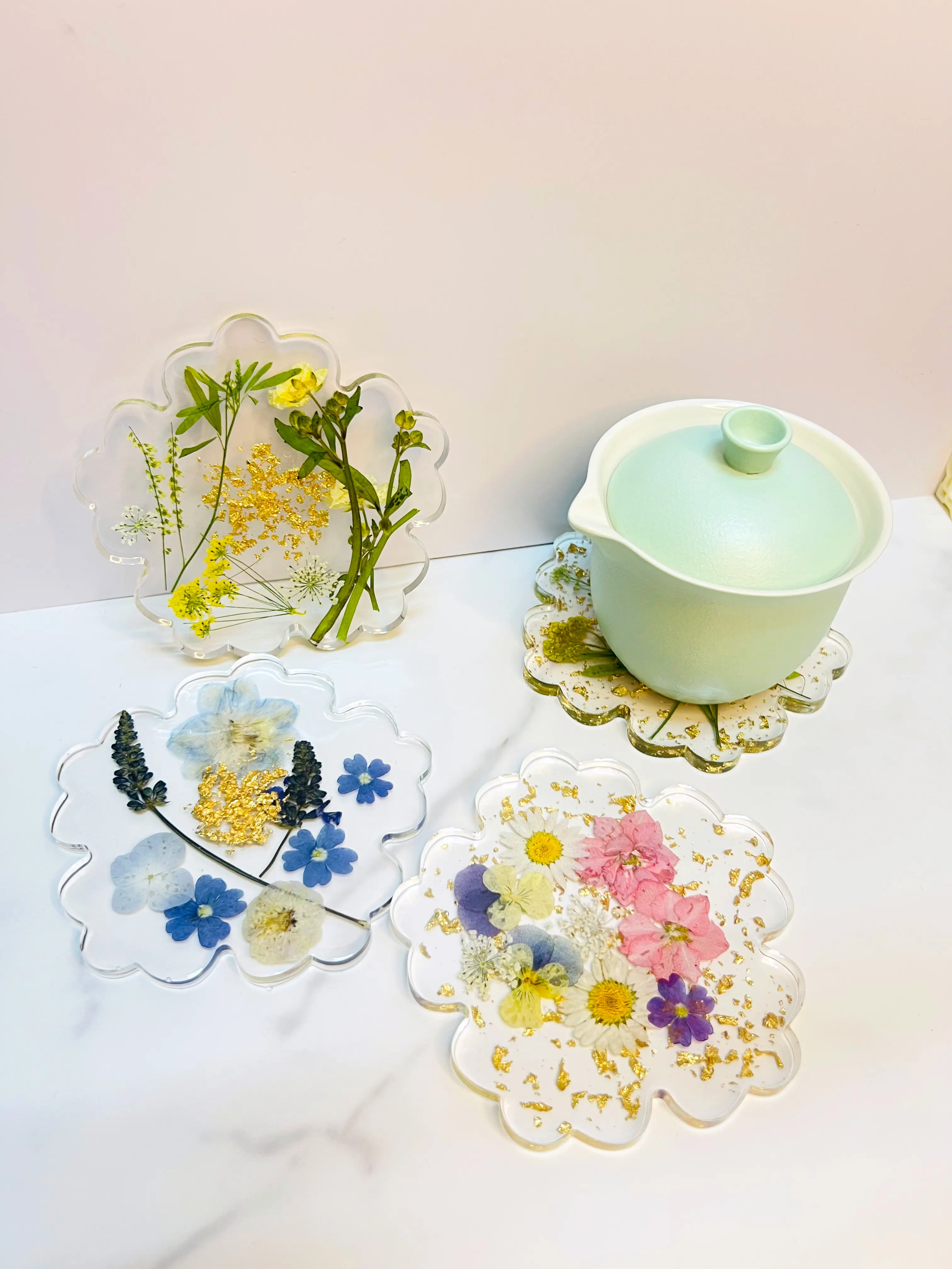 A collection of pressed-flower resin coasters in soft pastels